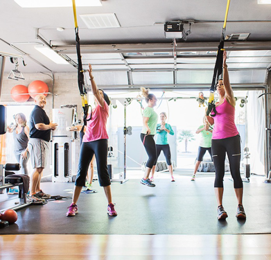 Members participating in a group fitness class using suspension trainers at Results Only Fitness gym.