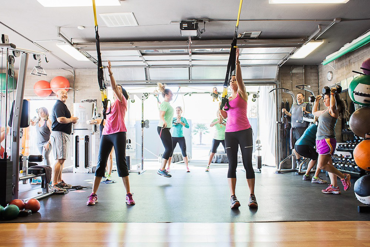 Members participating in a group fitness class using suspension trainers at Results Only Fitness gym.